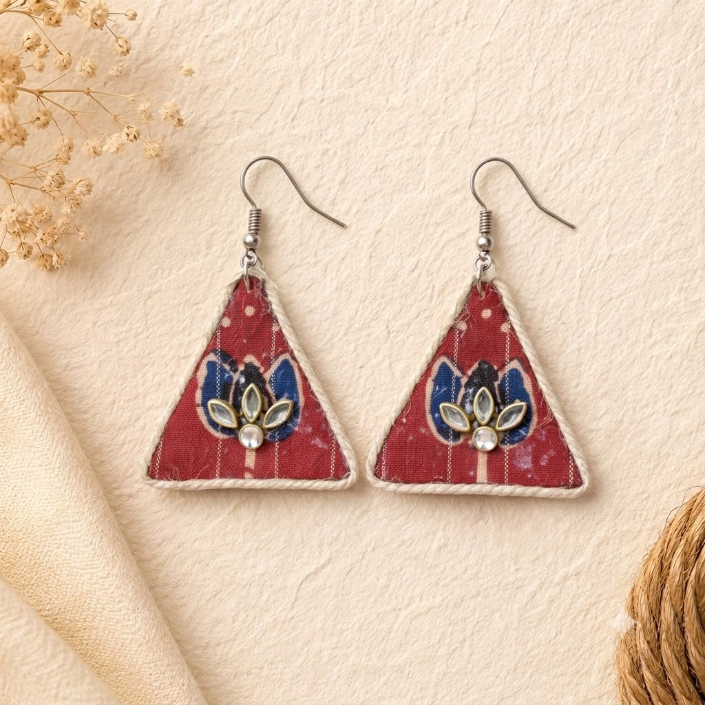 Triangular earrings with lotus floral design on a beige background with kundan