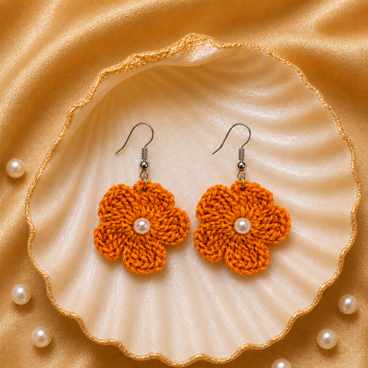 Orange crochet flower earrings with pearls on a shell and pearl background artisian touch