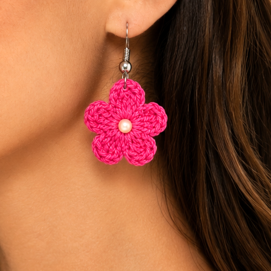 Close-up of a woman wearing pink flower earrings with a pearl center artisian touch