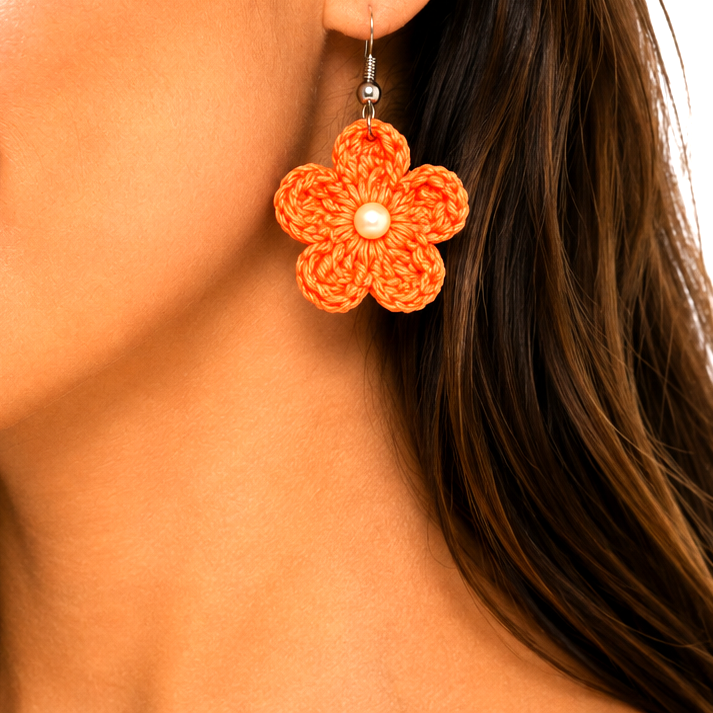 Close-up of a woman wearing orange flower earrings with a white artisian touch background