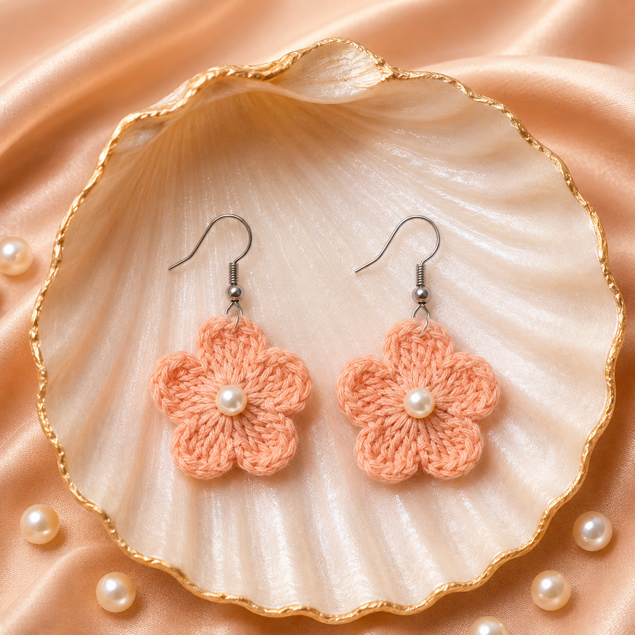 Pair of peach-colored flower earrings with pearls on a large shell and pearl background artisian touch
